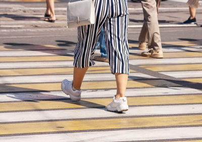 Low section of woman crossing road