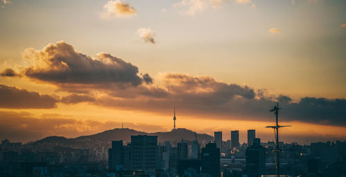 Buildings in city against cloudy sky