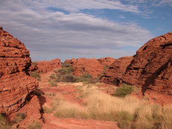 Rock formations on landscape against cloudy sky