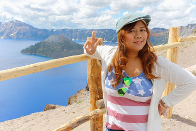 Portrait of smiling young woman standing against sky