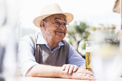 Portrait of happy senior man drinking glass of beer in a sidewalk cafe