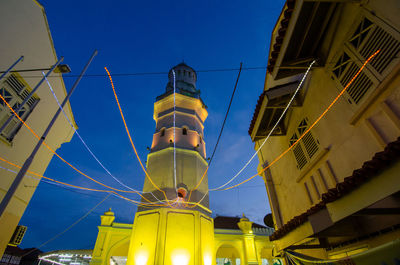 Low angle view of illuminated buildings against blue sky