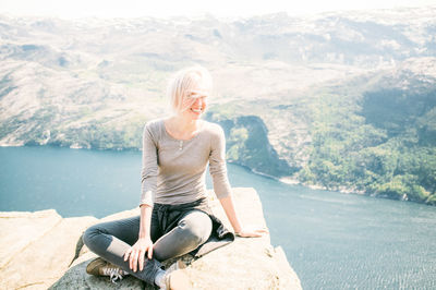 Full length of woman standing on cliff by sea