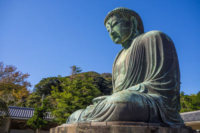Low angle view of giant buddha at kotoku-in against clear blue sky