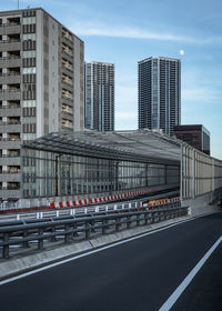 Road by buildings against sky in city