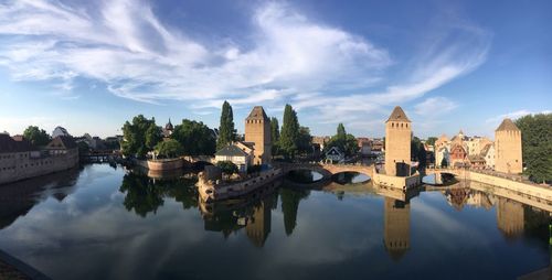 Bridge over river by buildings against sky