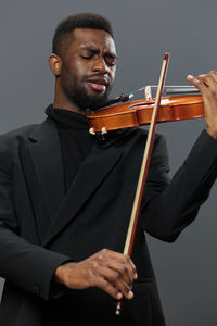 Midsection of man playing violin against white background