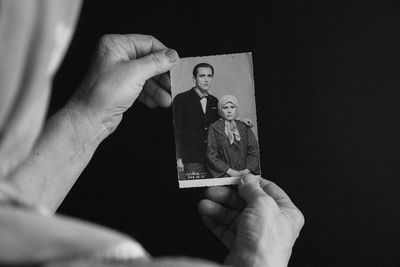 Close-up of hand holding paper against black background