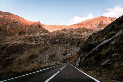 Road leading towards mountains against sky