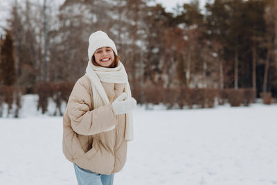 Portrait of smiling woman standing on snow covered field during winter