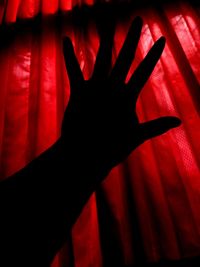 Shadow of person hand on red curtain