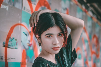 Portrait of young woman against graffiti wall