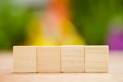 Close-up of blank wooden blocks on table against multi colored background