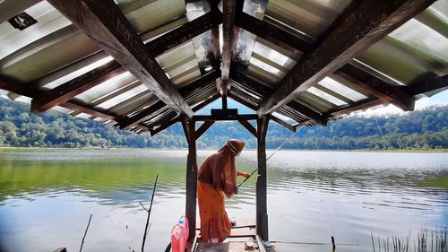 Rear view of young woman standing by lake