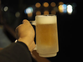 Close-up of hand holding beer glass on table