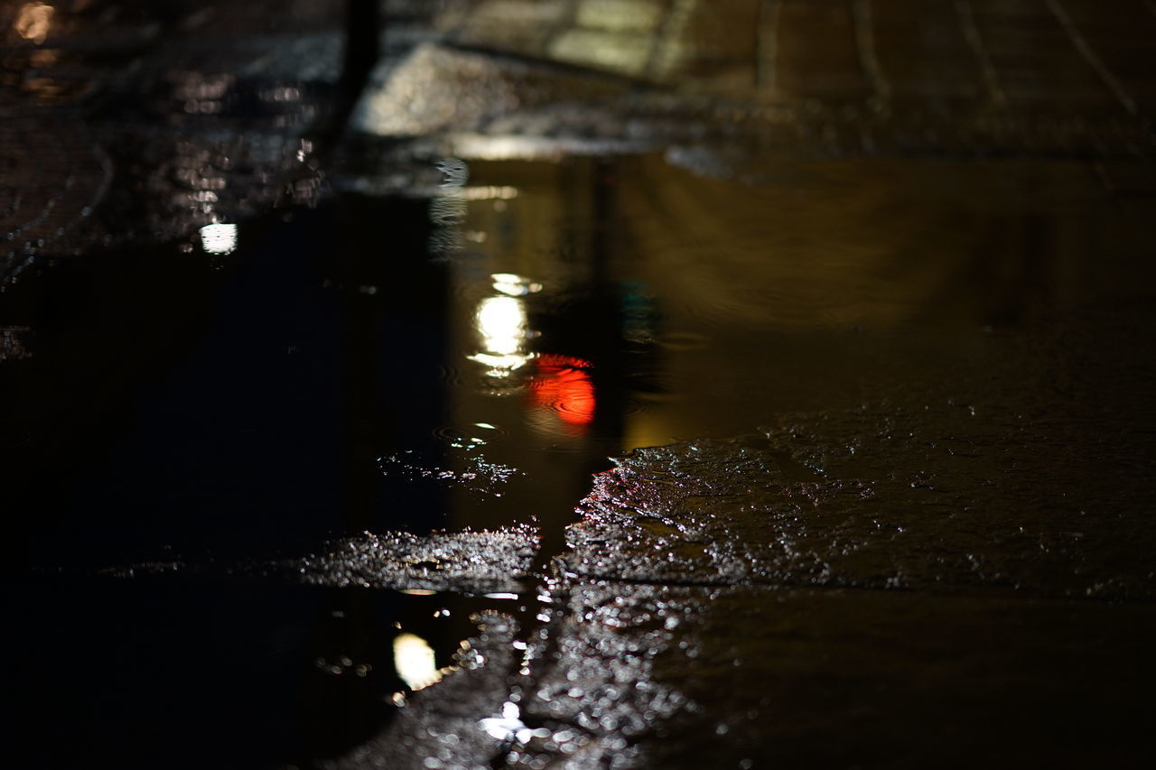 LOW SECTION OF ILLUMINATED WET CAR DURING RAINY SEASON AT NIGHT