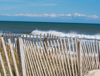 Wooden posts on beach against sky