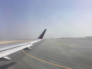 Cropped image of airplane on runway against sky