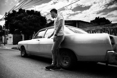 Side view of person standing by car on road