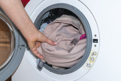 A woman's hand takes the laundry out of the washing machine	