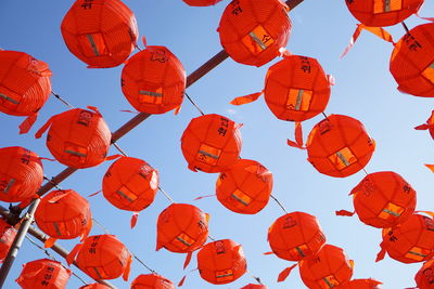 Low angle view of lanterns hanging against orange sky