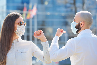 Man and woman wearing mask bumping elbow