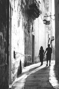 Rear view of people walking on street amidst buildings