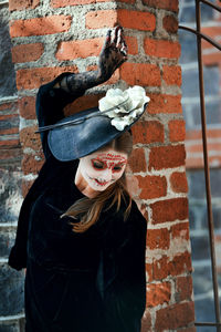 Portrait of woman standing against brick wall