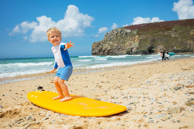 Full length of boy running on beach against sky