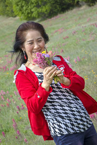 Woman holding red umbrella standing against plants