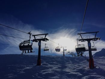 Low angle view of ski lifts against sky during winter