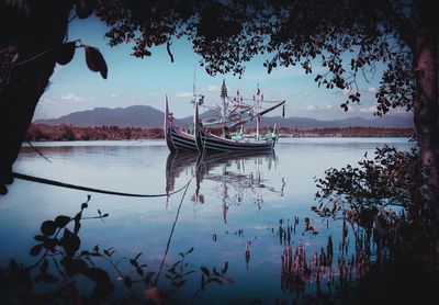 Sailboats moored in lake against sky