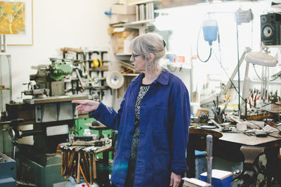 Senior female craftsperson pointing while working in jewelry workshop