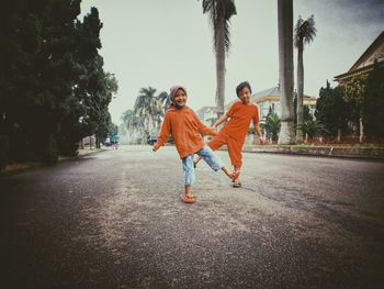 Full length of boy and girl walking on road