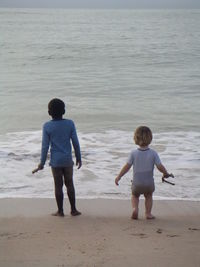 Rear view of boys standing on beach