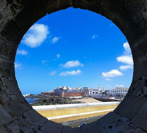 Buildings against blue sky seen through window