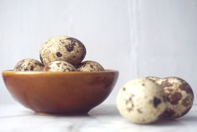 Close-up of quail eggs in bowl on marble