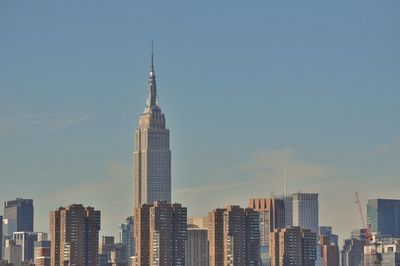 Skyscrapers in city against sky at dusk