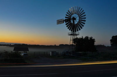 Silhouette wind turbine against clear sky during sunset