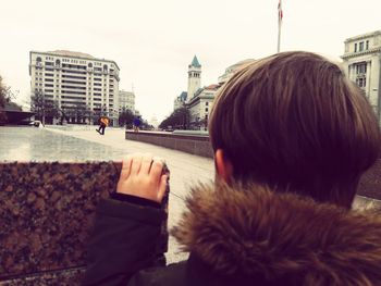 Rear view of man on street against buildings in city