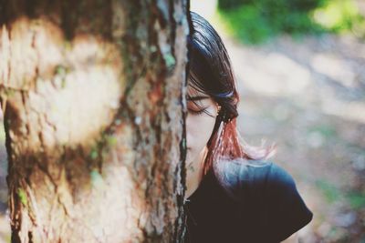 Close-up of woman behind tree