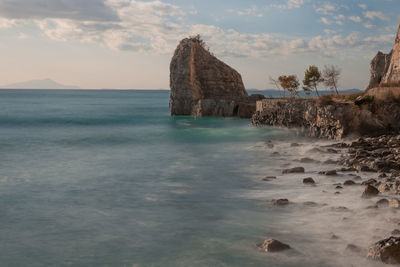 Scenic view of rock formation in sea against sky