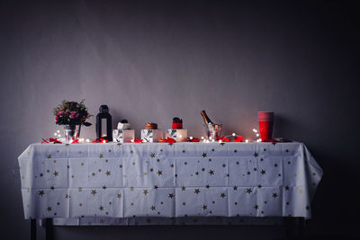 Close-up of red flower on table against wall