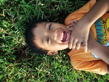 High angle portrait of boy lying on grass