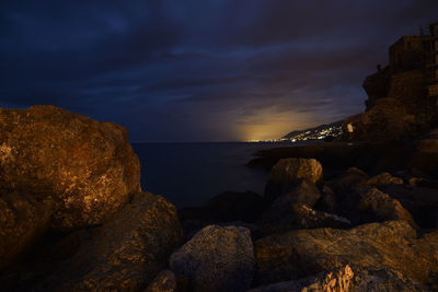 Rocks on beach against sky during sunset