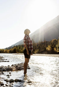 Austria, alps, woman on a hiking trip standing in a brook