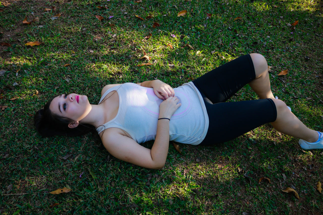 YOUNG WOMAN LYING DOWN ON GRASS