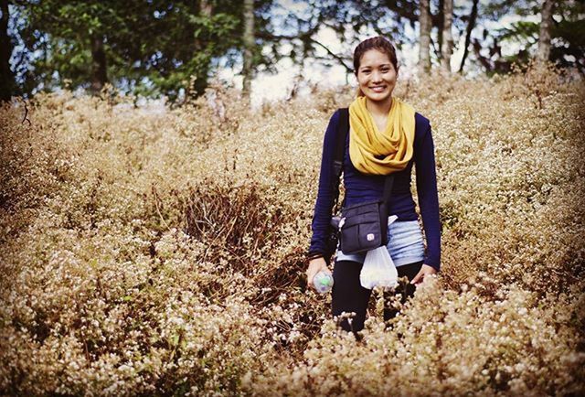 person, casual clothing, lifestyles, leisure activity, looking at camera, portrait, front view, standing, full length, tree, young adult, smiling, field, happiness, forest, growth, three quarter length, nature