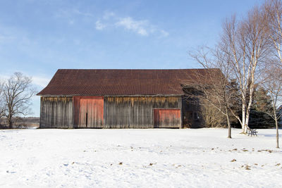 House on snow covered field against sky