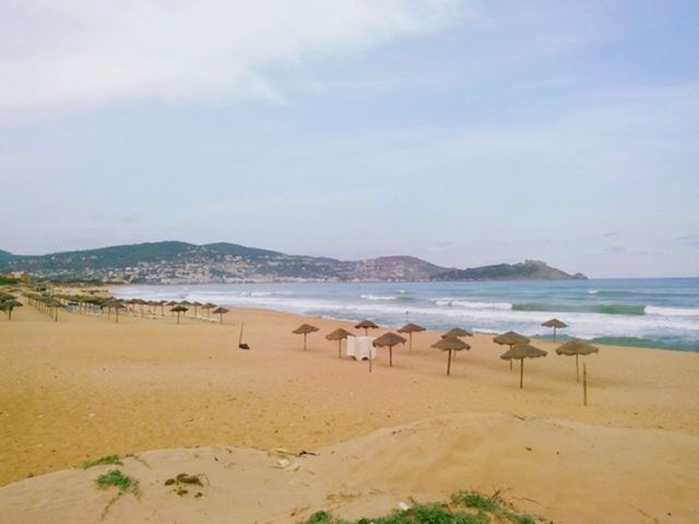 beach, sea, sand, water, shore, tranquil scene, scenics, sky, tranquility, mountain, beauty in nature, nature, coastline, idyllic, incidental people, horizon over water, day, outdoors, vacations, non-urban scene